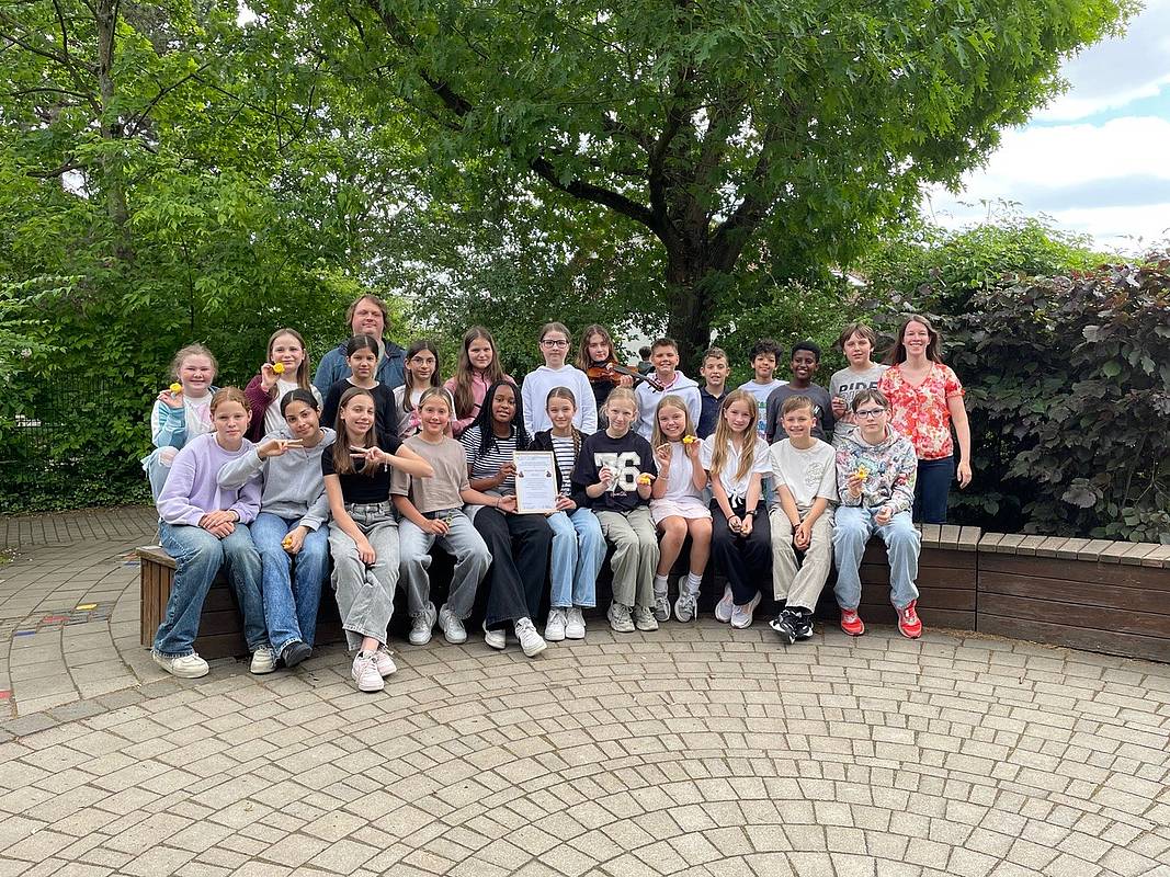 Schülerinnen und Schüler der 5a sitzen mit Filmteam, Komponisten und Musiker